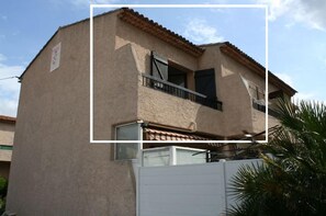 A two-story building with a beige stucco exterior, a tiled roof, and a balcony with metal railings. - Le Pradet - Studio 4 pers à 10min à pied de la Plage - Roses (Le Pradet)