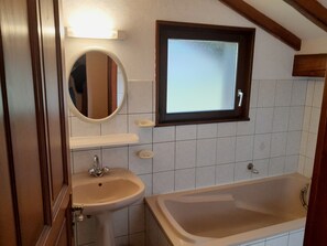 A bathroom with a sink, mirror, and bathtub.