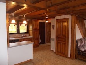 A kitchen with wooden cabinets, a white countertop, and a window with curtains.