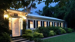 A white building with black shutters, a number 409 sign, and a well-maintained garden with various plants and a lawn.