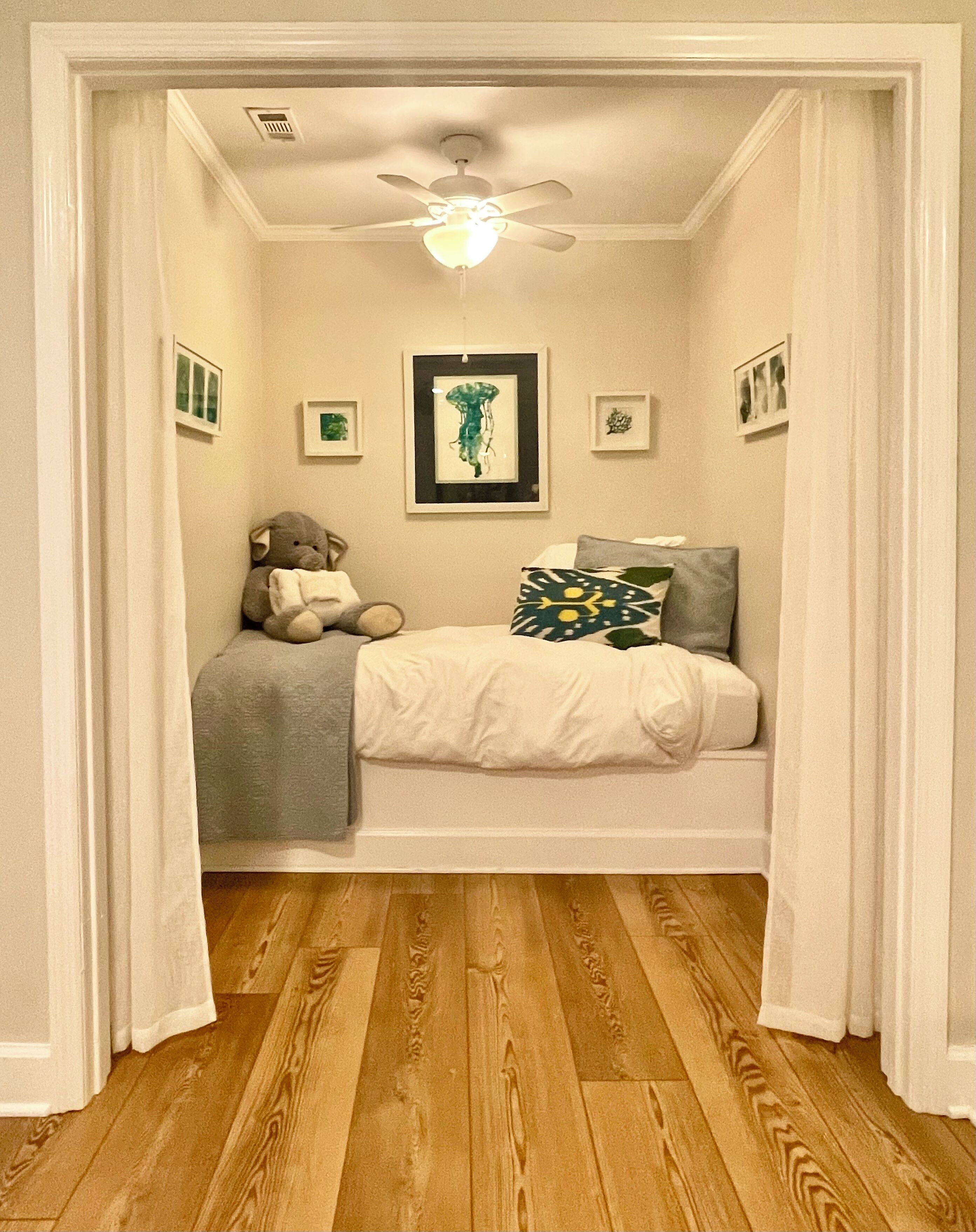 A bedroom with a bed, a ceiling fan, and a teddy bear.