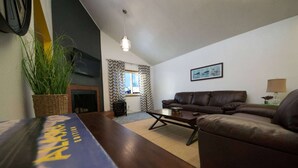 Un salon avec un canapé, une table basse, une cheminée et une plante.