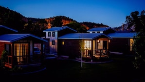 A row of modern houses with solar panels, a clear sky, and a hilly landscape in the background. - Tiny Home near Zion with Loft & Resort Pools (Orderville)