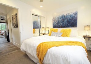 Ein Hotelzimmer mit einem großen Bett, einem Gemälde an der Wand und Blick ins Freie.