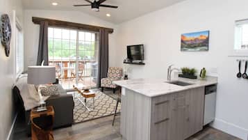 A modern kitchen with a central island, a dining area with a table and chairs, and a large window with curtains.