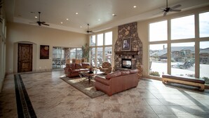 A spacious living room with a stone fireplace, leather sofas, and large windows offering a view of the outside. -  St George, near Zion 2 king beds, 2 pools/hot tubs, fish pond  (Washington)