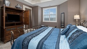 Ein Schlafzimmer mit Bett, Fernseher, Kommode und Fenster.