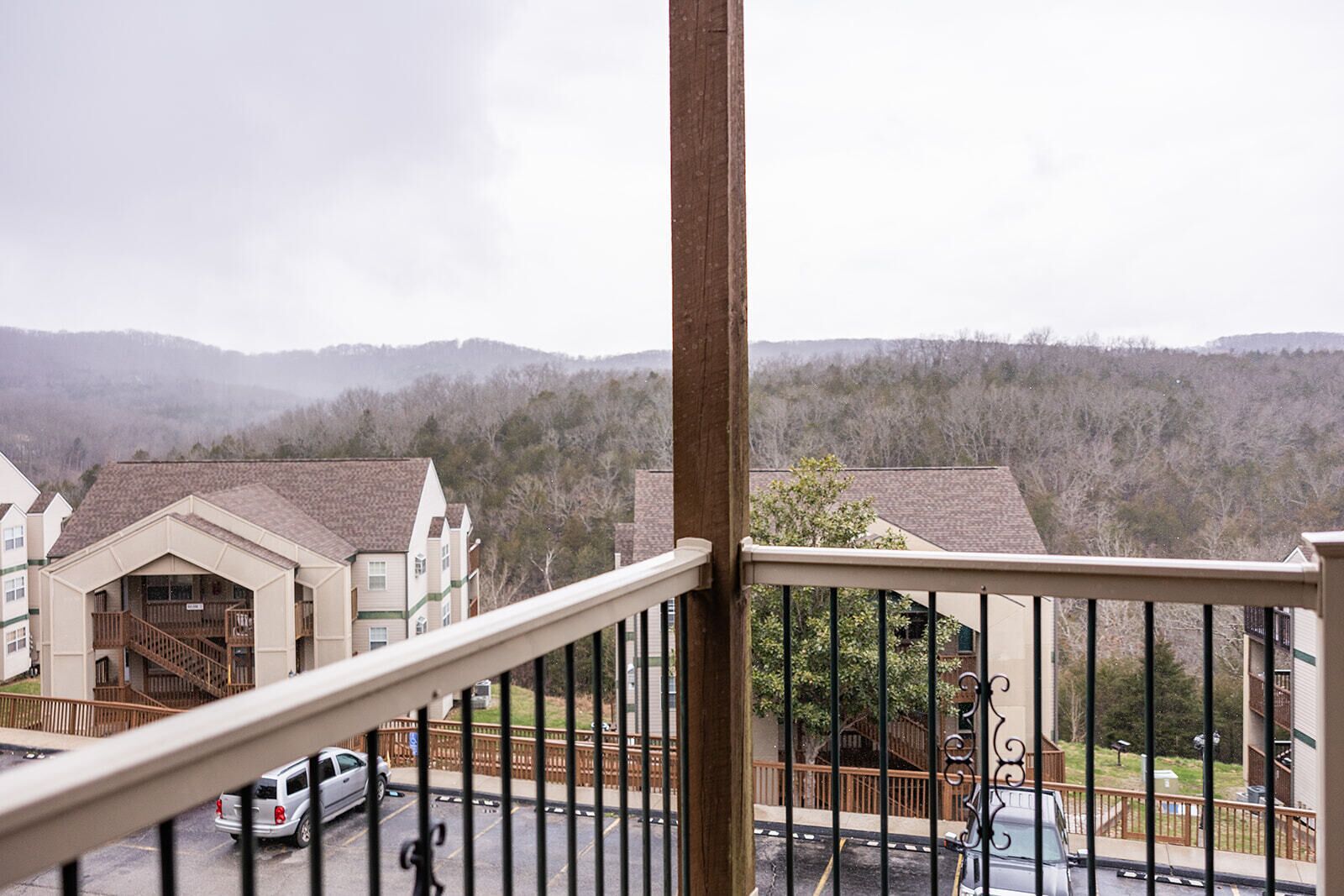 A residential building with a balcony, a staircase, and a view of a hilly landscape.