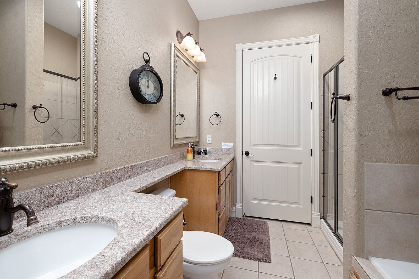 A bathroom with a vanity, sink, mirror, toilet, and shower.