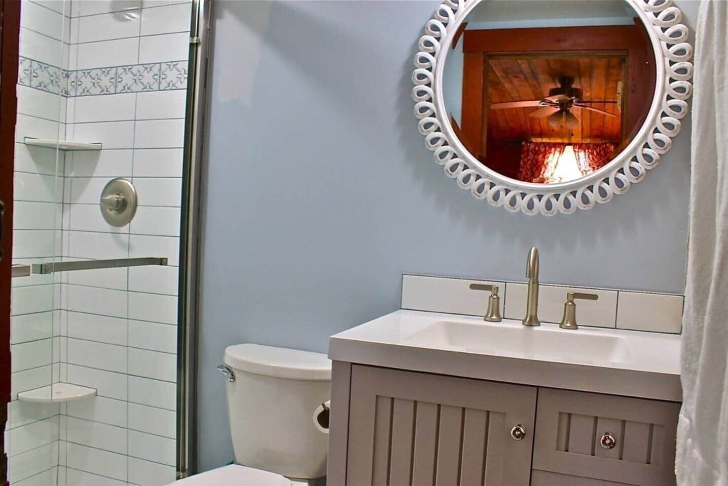 A bathroom with a shower, toilet, and vanity with a mirror.