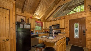 A wooden cabin kitchen with a refrigerator, microwave, and wooden cabinets.