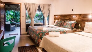 A hotel room with a bed, a chair, a small table, and a view of a garden through a window. - Large Bungalow in Banana Beach, with King and Queen Bed. A/C, Wifi, Kitchenette (Santa Teresa Costa Rica)