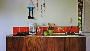 A kitchen with a coffee maker, a sink, and wooden cabinets. - Large Bungalow in Banana Beach, with King and Queen Bed. A/C, Wifi, Kitchenette (Santa Teresa Costa Rica)