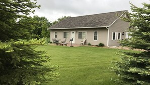 A two-story house with a well-maintained lawn and a patio area with outdoor furniture.