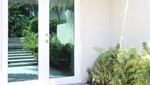 Eine Glastür führt zu einem Garten mit Stufen und viel Grün.