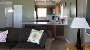 Una cocina moderna con una isla central, armarios de madera y un comedor con sofá y lámpara.