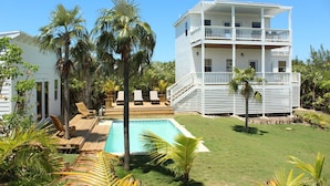 A multi-story building with a pool, surrounded by palm trees and a well-maintained lawn.