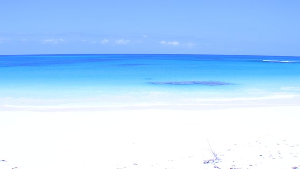 A beach with clear blue water and a sandy shore.
