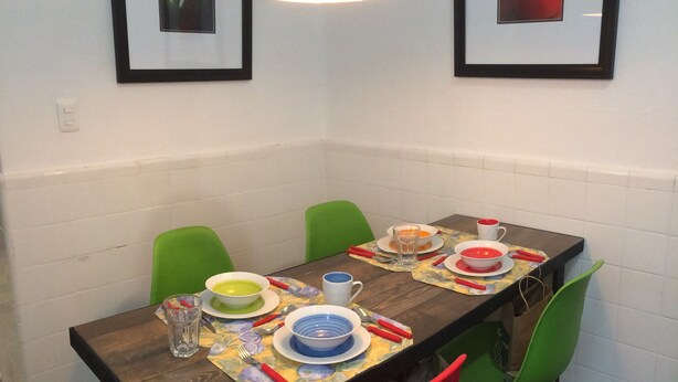 A dining table set with plates, bowls, and cutlery, surrounded by green chairs.