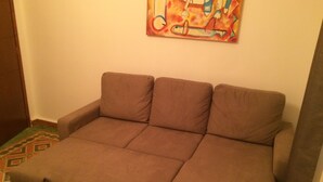 A brown sofa in a room with a colorful painting on the wall.