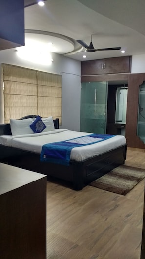 A modern bedroom with a bed, a desk, and a ceiling fan. - single room Hitech Shilparamam Guest House (Hyderabad)