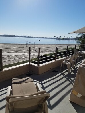 Een terras aan het strand met lounge stoelen en uitzicht op het strand en de oceaan.