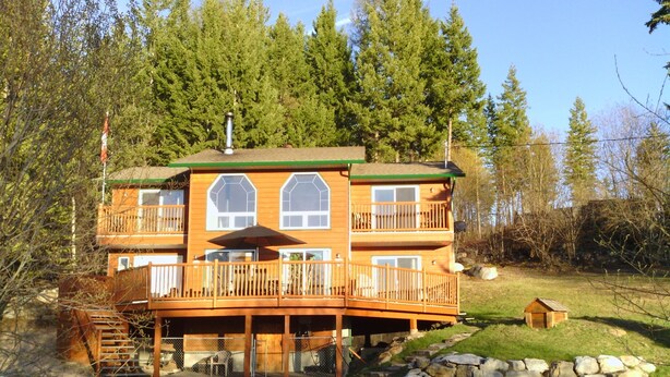 A multi-story wooden cabin with balconies, a deck, and a stone foundation. - Quiet Peaceful Carmi Mountain Home. (Penticton)