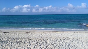 A beach with clear blue water and a sandy shore.