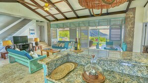 Un amplio salón con televisor grande, asientos y vistas al exterior.
