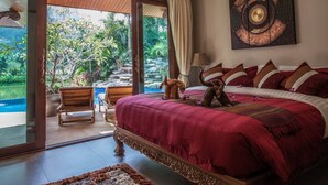 Une chambre dotée d’un grand lit, offrant une vue sur une piscine, et comprenant un coin repas avec une table et des chaises.