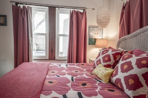 Ein Schlafzimmer mit Bett, Vorhängen, einer Lampe und einem Fenster.