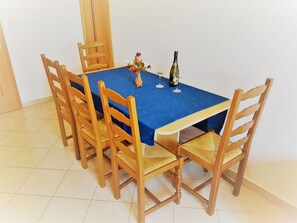 A dining table with a blue tablecloth, surrounded by wooden chairs with woven seats.