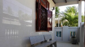 A bench outside a building with tiled walls and a wooden door.