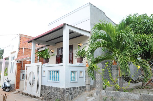 Une maison d’habitation dotée d’un porche couvert, de plantes en pot et d’un mur en pierre.