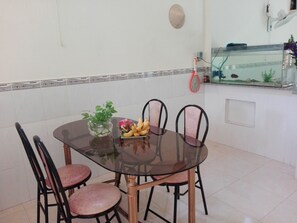 Une table à manger avec des chaises, un vase rempli de fleurs et une assiette de fruits.