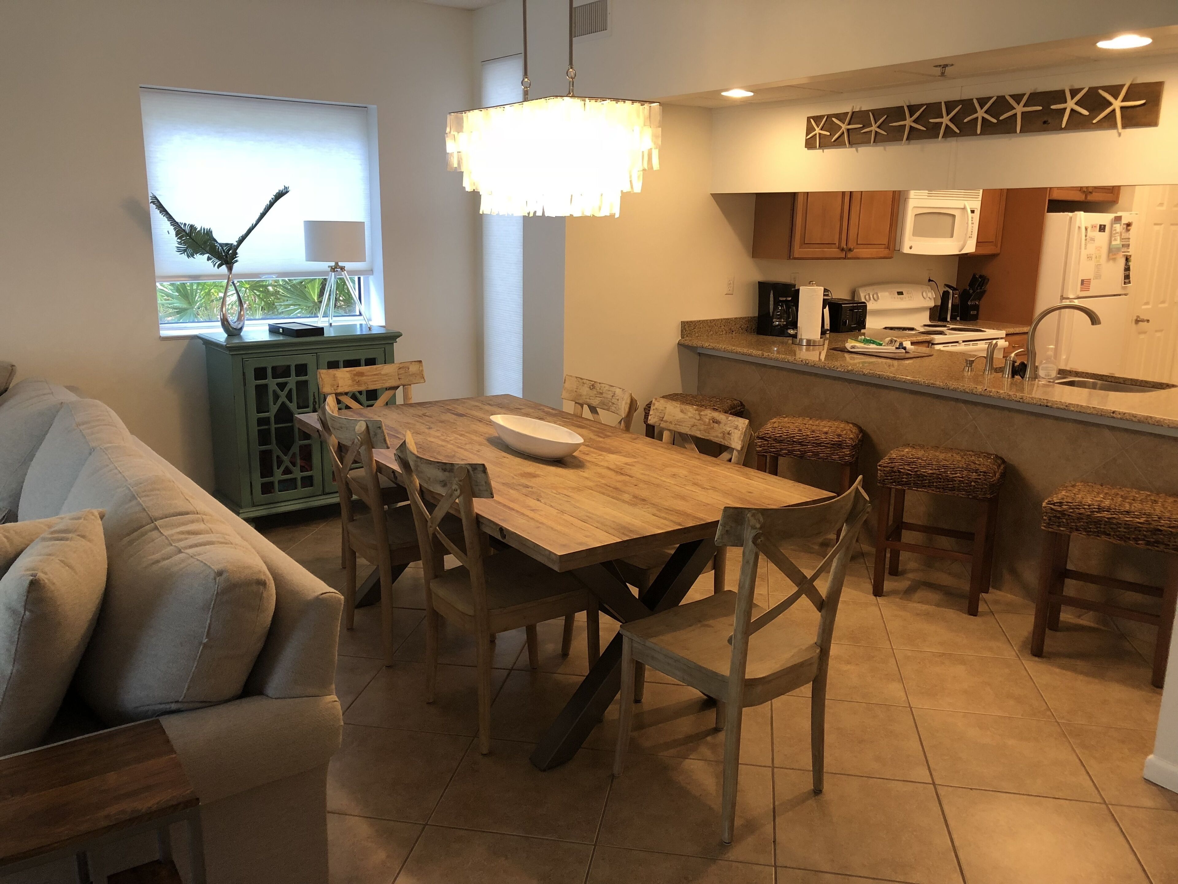 Una cocina moderna con una mesa de comedor de madera, taburetes de bar y un microondas integrado.