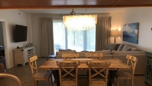 Un salon comprenant une table à manger en bois, des chaises, un canapé, un téléviseur et un lustre.