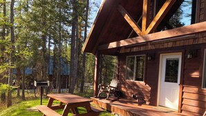 A wooden cabin with a porch, picnic table, and rocking chair. - The Ridge At Glacier / Alpine Cabin #5 (Coram)