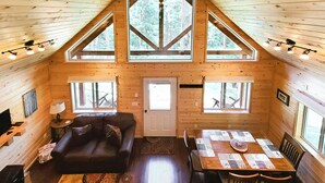 A cozy cabin interior with a wooden interior, a sofa, a dining table, and large windows. - The Ridge At Glacier / Alpine Cabin #5 (Coram)