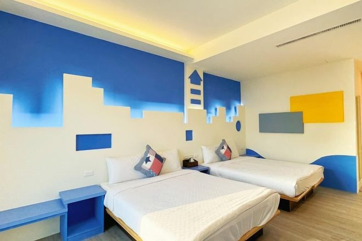 Een hotelkamer met twee bedden, een bureau en een stoel.