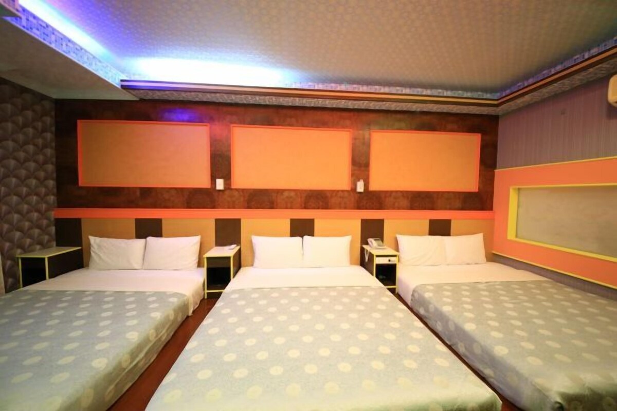 Une chambre d’hôtel avec deux lits, un grand miroir et une tête de lit dotée d’un éclairage intégré.