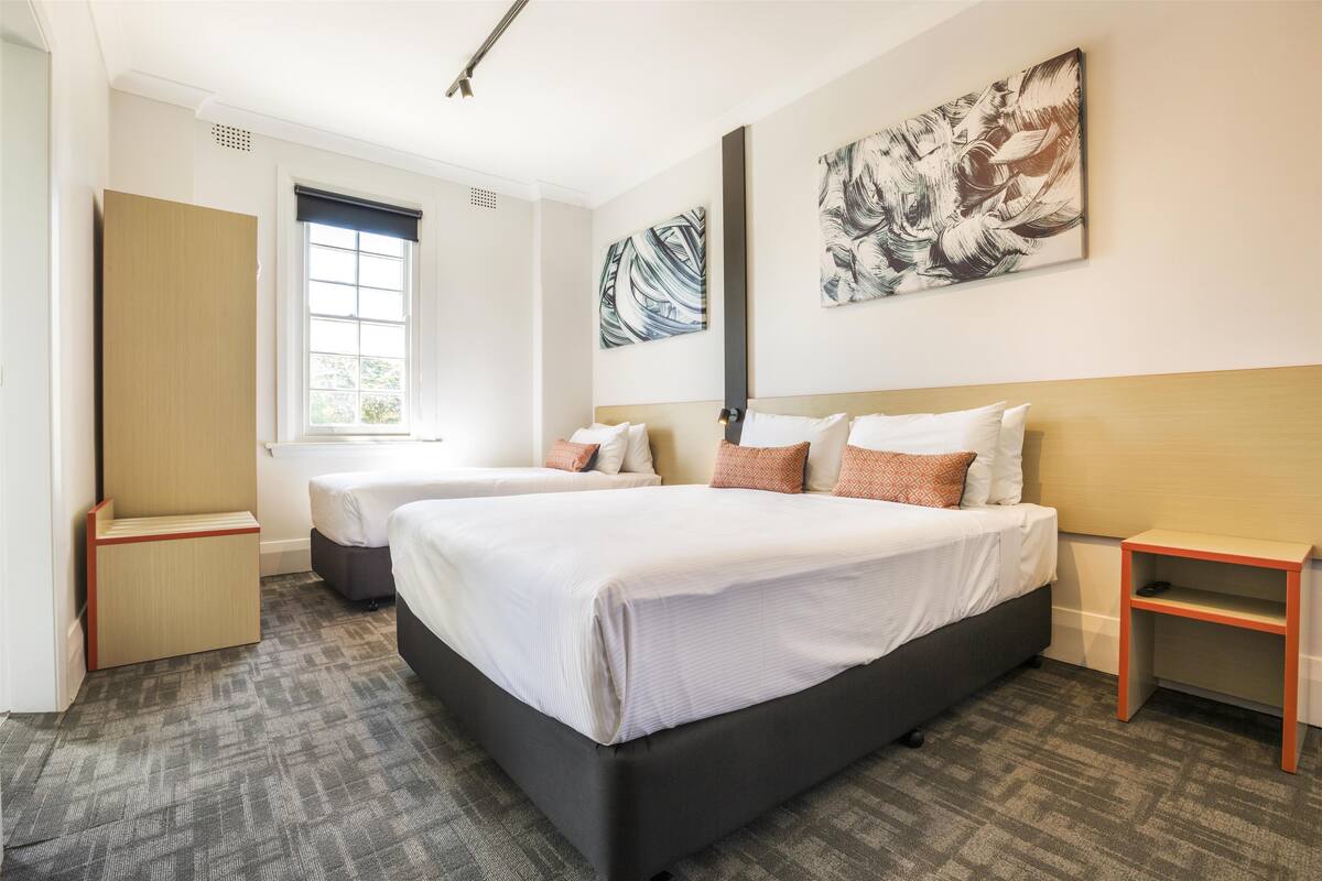 Una habitación de hotel con dos camas, un ventanal grande y obras de arte en las paredes.