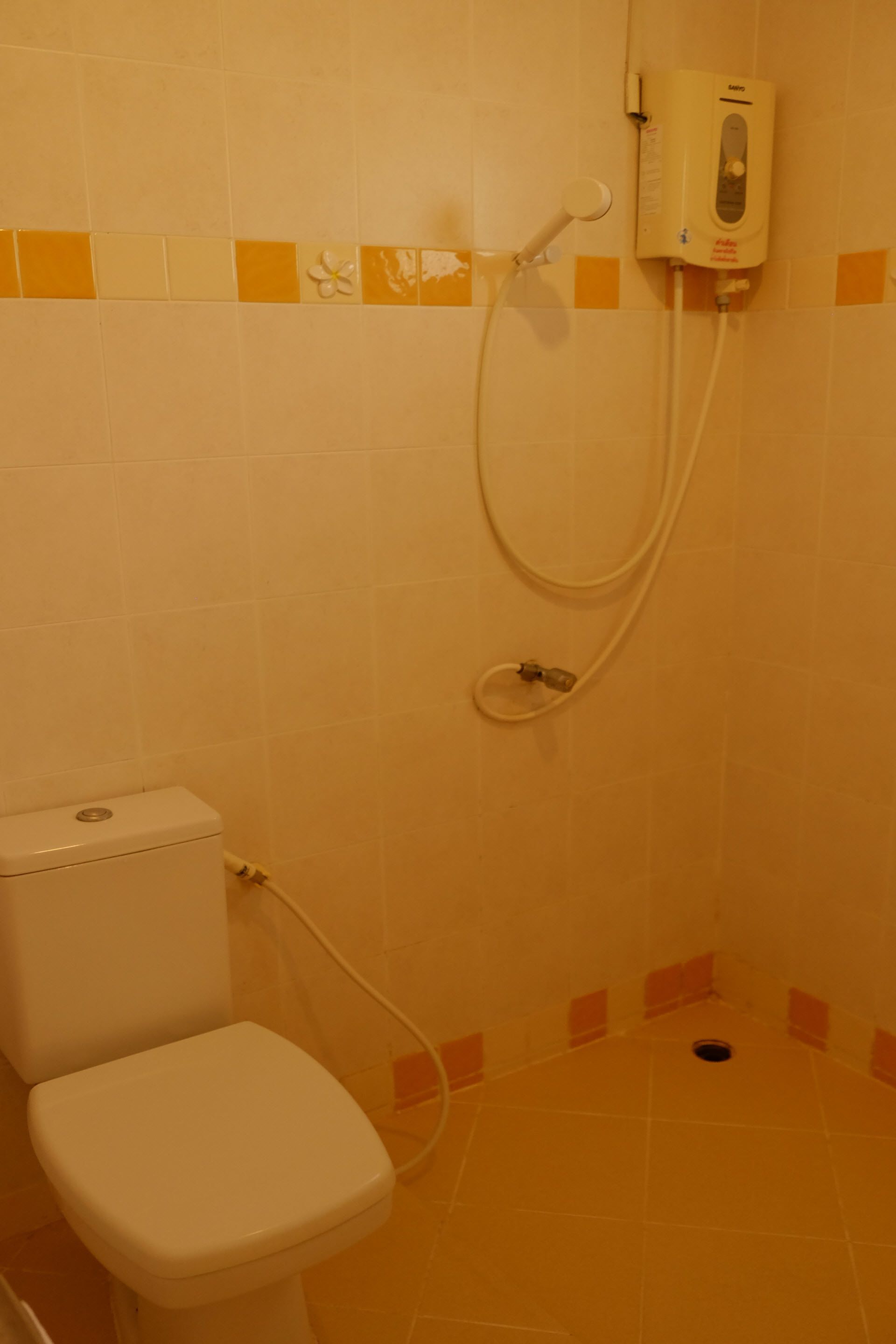 Une petite salle de bain comprenant des toilettes, une douche et un distributeur de savon fixé au mur.