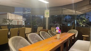 A modern dining area with a wooden table, cushioned chairs, and a vase of flowers.