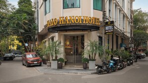 Das Hotel Halo Hanoi mit einer markanten Eingangspforte, Blumentöpfen und geparkten Fahrzeugen.