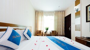 Quarto de hotel com uma cama bem arrumada, uma escrivaninha e uma cadeira.