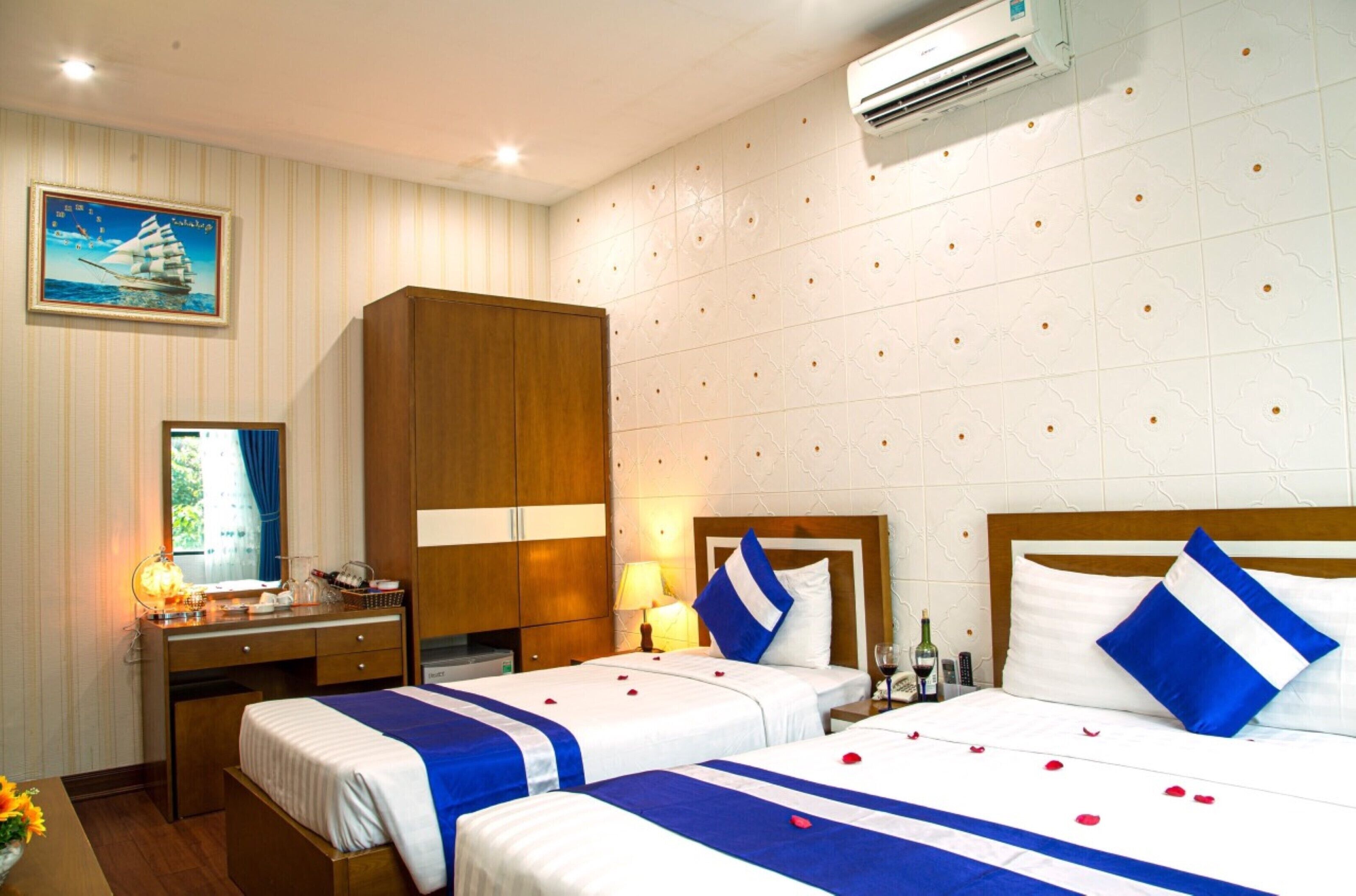 A hotel room with two beds, a desk, and a wardrobe.