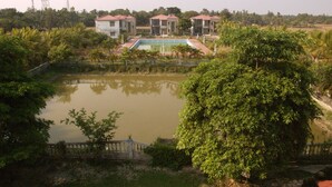 A residential area with a swimming pool, surrounded by lush greenery and a few houses. - Hotel Deepak (Kakdwip)