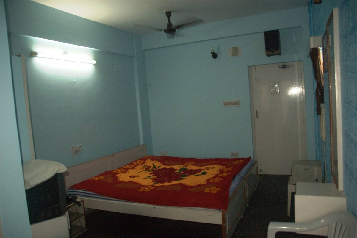 Un dormitorio con cama, escritorio, silla, armario y ventilador de techo.