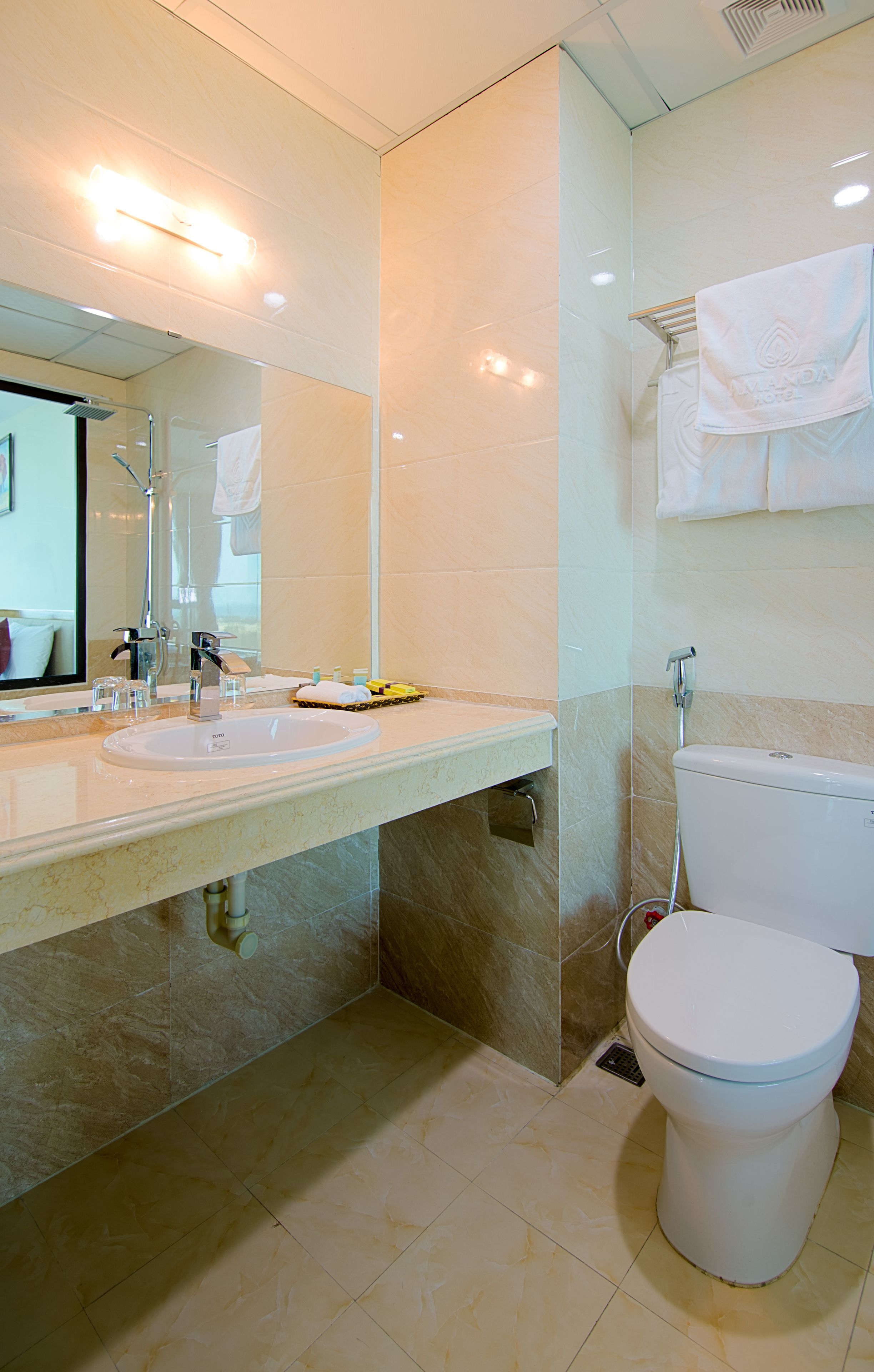 A modern bathroom with a large mirror, a sink, a toilet, and a shower area.